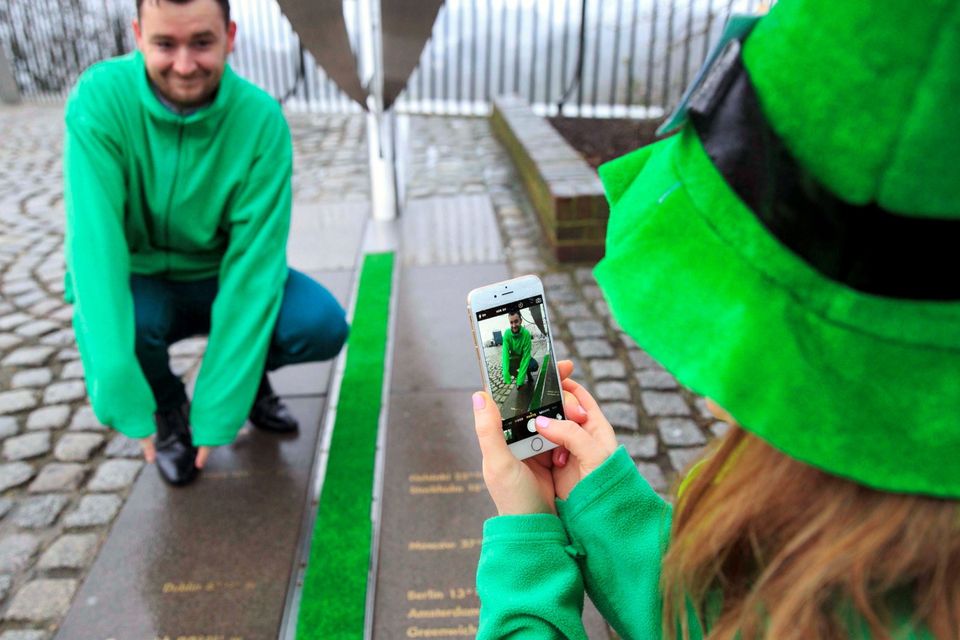 Ciara Kelly photographs Gareth Maguire on a mobile phone by the Meridian Line at the Royal Observatory in Greenwich, south east London, which is decorated green by Tourism Ireland to celebrate St Patrick's Day, which is on Tuesday 17th March.