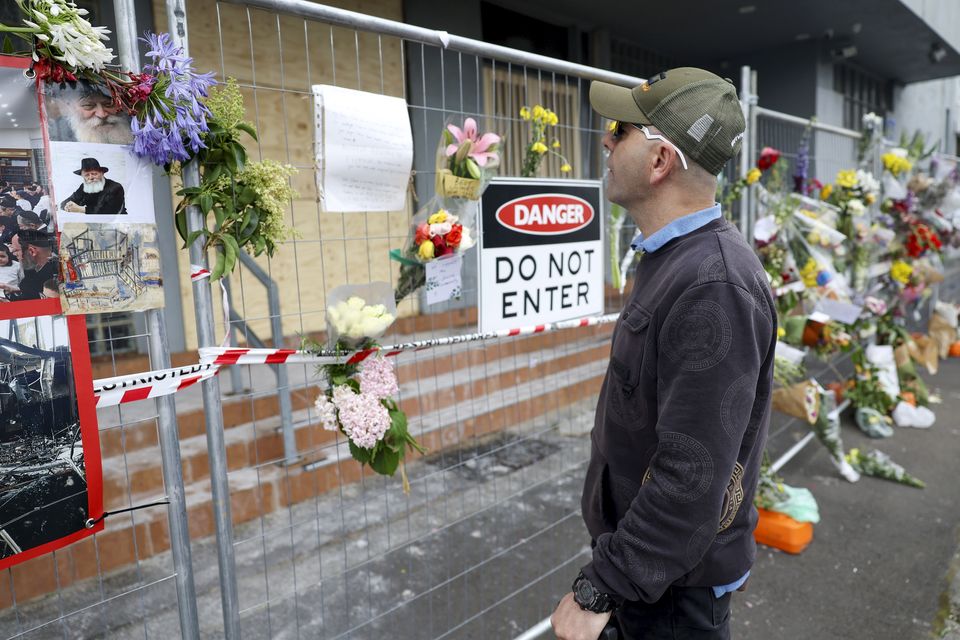 A man reads messages left on the fence outside the fire damaged Adass Israel Synagogue in Melbourne (Con Chronis/AAP/AP)