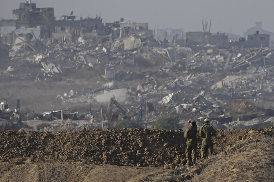 Israeli soldiers look at a destroyed part of Gaza City from their position at the Israel-Gaza border (Tsafrir Abayov/AP)