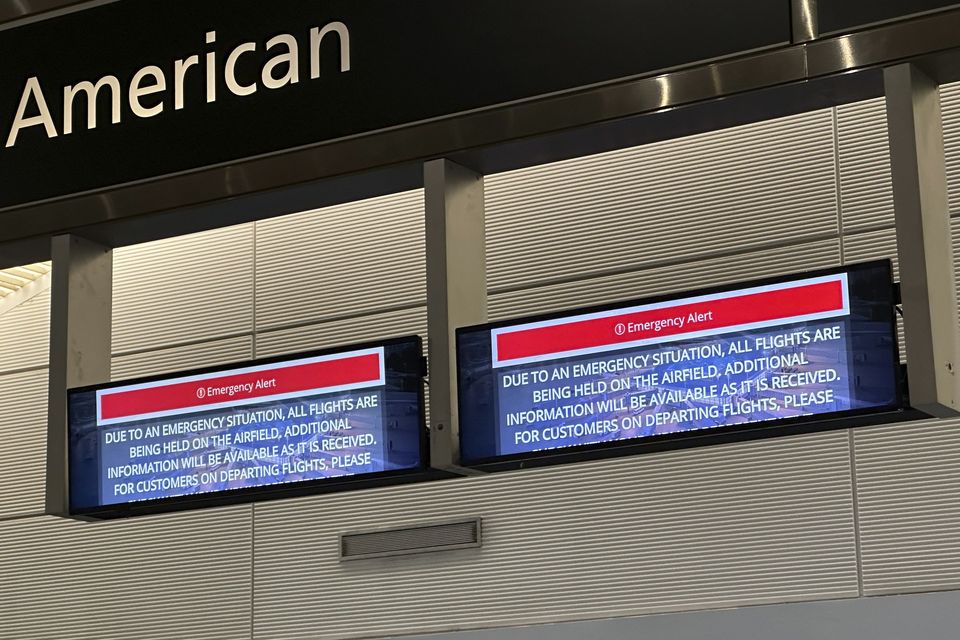 Signs display an emergency alert above an American Airlines counter in the terminal at Ronald Reagan Washington National Airport (Jeannie Ohm/AP)