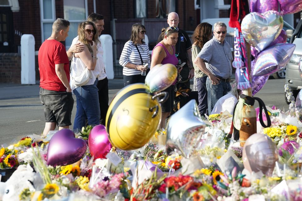 People look at floral tributes on Maple Street, Southport (Danny Lawson/PA)