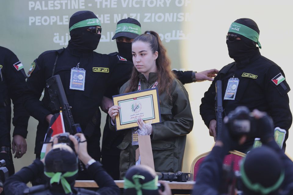 Israeli soldier Agam Berger stands with masked Islamic Jihad militants as she is handed over to the Red Cross at the Jabalya refugee camp in Gaza City (Mohammed Hajjar/AP)