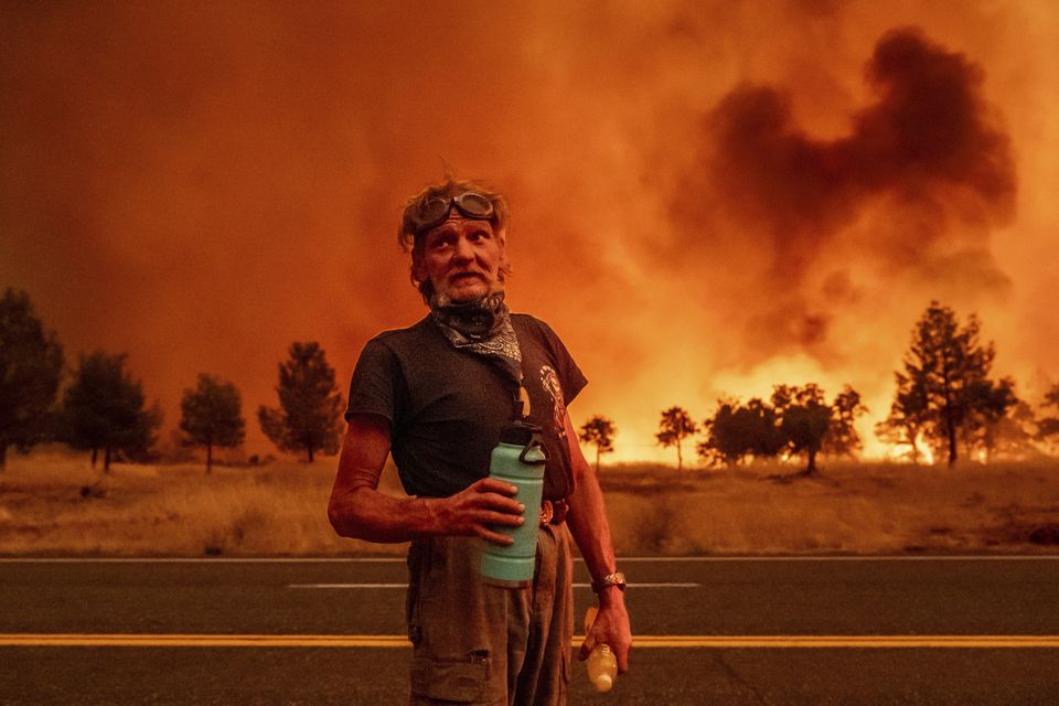 Grant Douglas pauses to drink water while evacuating as the Park Fire jumps Highway 36 near Paynes Creek in Tehama County, California (Noah Berger/AP)