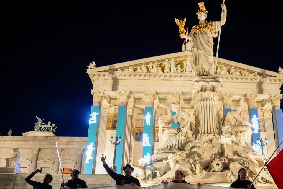 Anti-right-wing protesters shout slogans and hold a banner that reads “Don’t let Nazis rule and never let them march” in front of the parliament building in Vienna (Andreea Alexandru/AP)