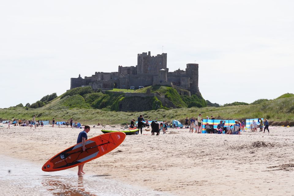 People enjoy the warm weather on Bamburgh Beach in Northumberland (Owen Humphreys/PA)