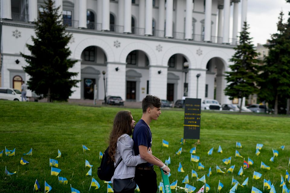 A couple ride a scooter in front of flags in Independence Square honouring soldiers killed fighting Russian troops (Natacha Pisarenko/AP)