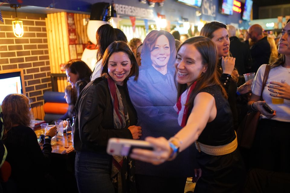 People pose for photos with a cardboard cutout of Kamala Harris at the Democrats Abroad US election watching event in central London (Yui Mok/PA)