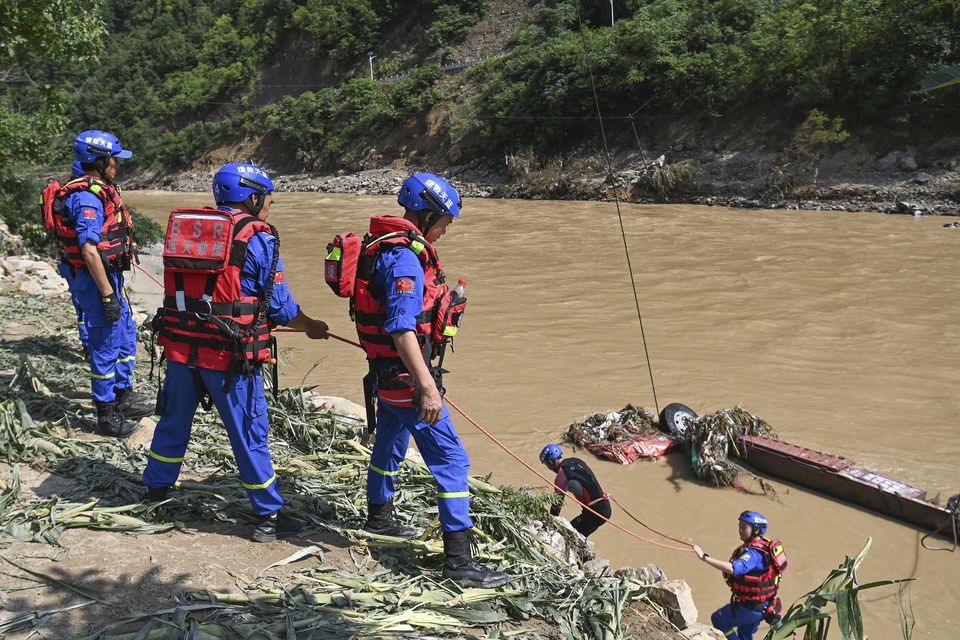 Rescue workers search for victims in the aftermath of a bridge collapse that sent vehicles and people into a river (Zou Jingyi/Xinhua via AP)