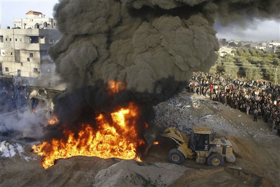 A bulldozer tries to push sand on a fire after an Israeli missile strike on a building in the Rafah refugee camp, southern Gaza Strip, Sunday, Dec. 28, 2008. Gazans covered in their homes Sunday as Israeli warplanes pressing one of Israel's deadliest assaults ever on Palestinian militants unleashed missiles on weapons warehouses, a police station, the homes of militant field commanders and dozens of other targets across the Hamas-ruled Gaza Strip. (AP Photo/Hatem Omar,MaanImages)