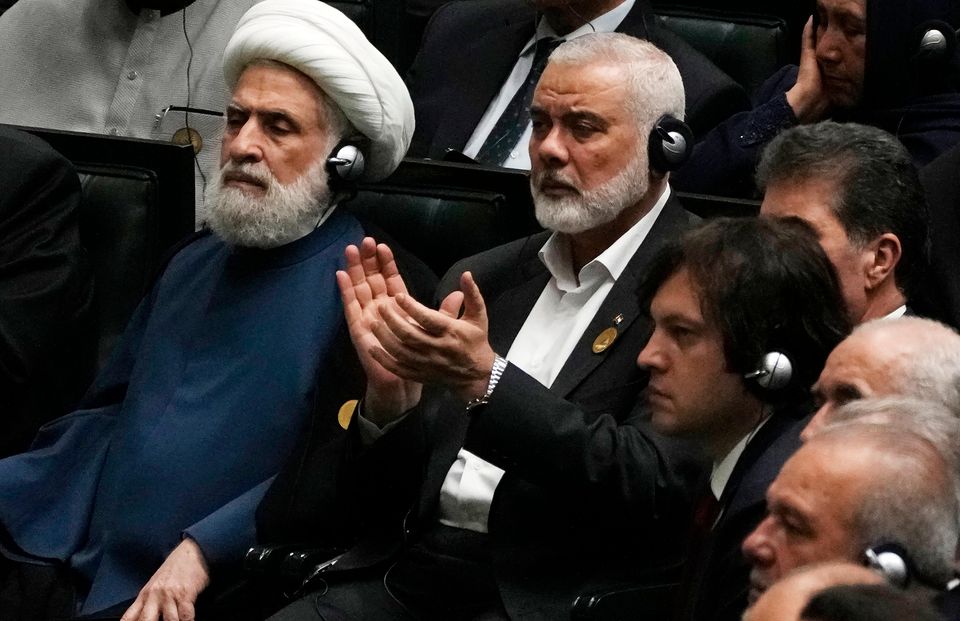 Ismail Haniyeh claps as newly elected Iranian President Masoud Pezeshkian speaks while deputy leader of the Lebanese militant group Hezbollah, Sheikh Naim Kassem, left, sits during the swearing-in ceremony of Mr Pezeshkian in Tehran on Tuesday (Vahid Salemi/AP)