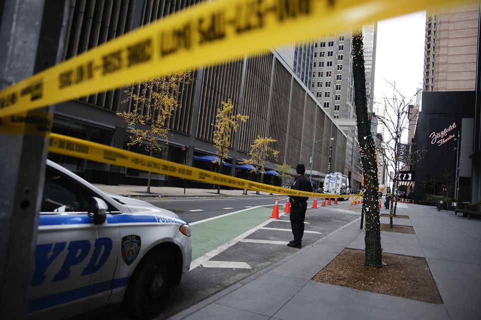 A New York police officer stands on 54th Street outside the Hilton Hotel in midtown Manhattan where Brian Thompson was fatally shot (Stefan Jeremiah/AP)