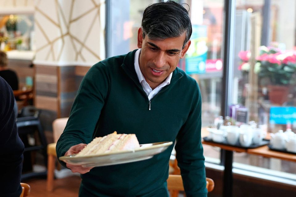 Prime Minister Rishi Sunak helps himself to a cake as he chats with members of the public at a garden centre in Crawley yesterday (Photo by Henry Nicholls - WPA Pool/Getty Images)