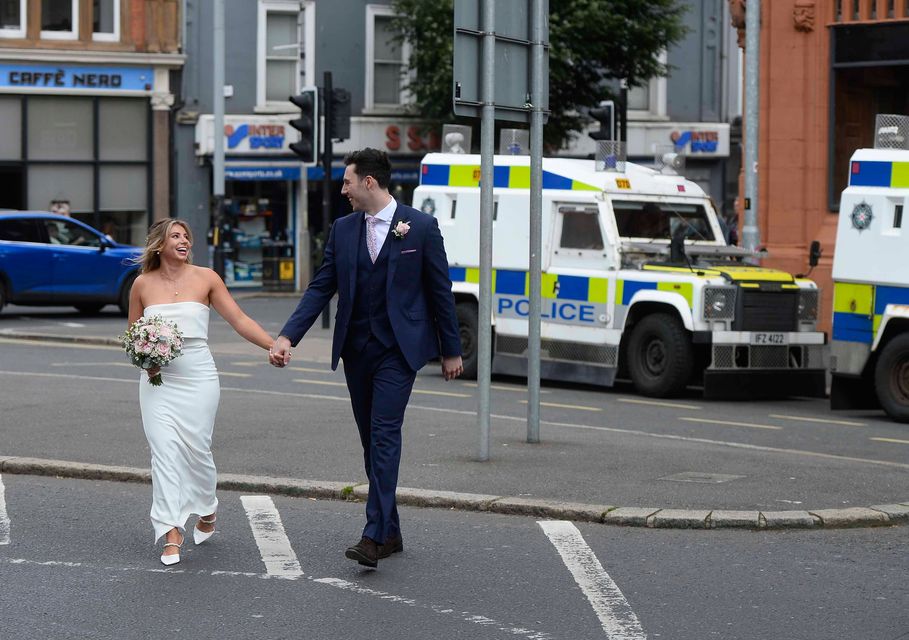 A newly married couple cross the road as PSNI officers line the streets. Credit: Mark Marlow/PA Media Assignments/PA Wire