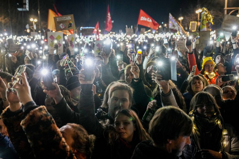 People hold up their cell phones as they protest against the far-right Alternative for Germany party (Ebrahim Noroozi/AP)