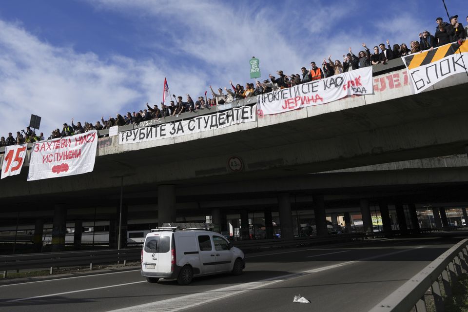 Students stand on a bridge during the protest, with banners reading ‘Requirement is not met’ and ‘Honk for students’ (Darko Vojinovic/AP)