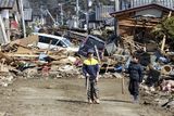 thumbnail: Young residents of the seaside town of Toyoma, northern Japan, walk amongst the debris around their homes Monday, March 14, 2011, three days after a giant quake and tsunami struck the country's northeastern coast. (AP Photo/Mark Baker)