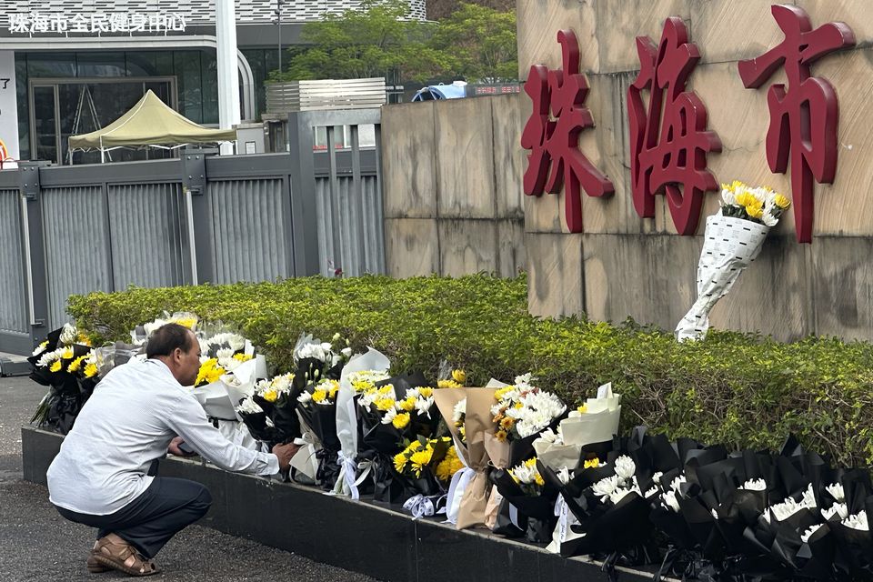 A man offers flowers outside the Zhuhai People’s Fitness Plaza (AP Photo/Ng Han Guan)