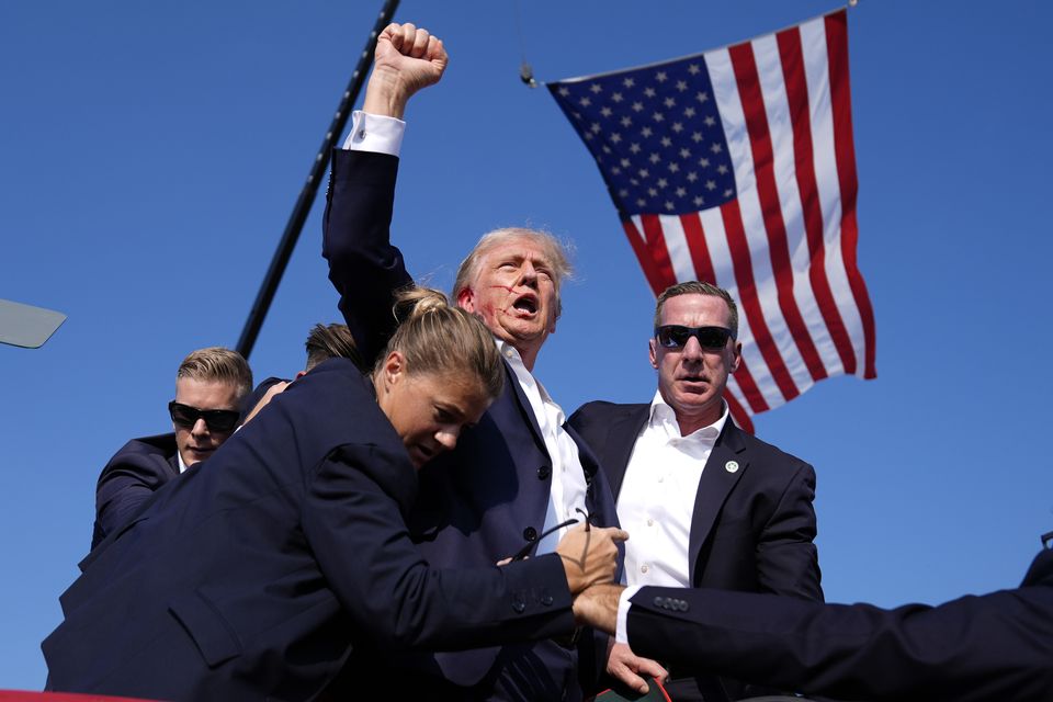 Donald Trump, surrounded by Secret Service agents, raised his fist as he left the stage following the assassination attempt (Evan Vucci/AP)