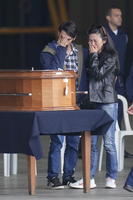 Family members of a plane crash victim stand by their remains during a religious ceremony shortly before they are placed in an air force plane (Andre Penner/AP)