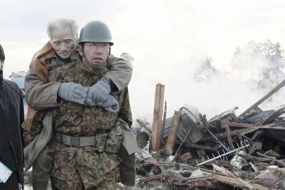 An elderly man is carried by a Self-Defense Force member in the tsunami-torn Natori city, Miyagi Prefecture, northern Japan, Saturday morning, March 12, 2011, one day after strong earthquakes hit the area
