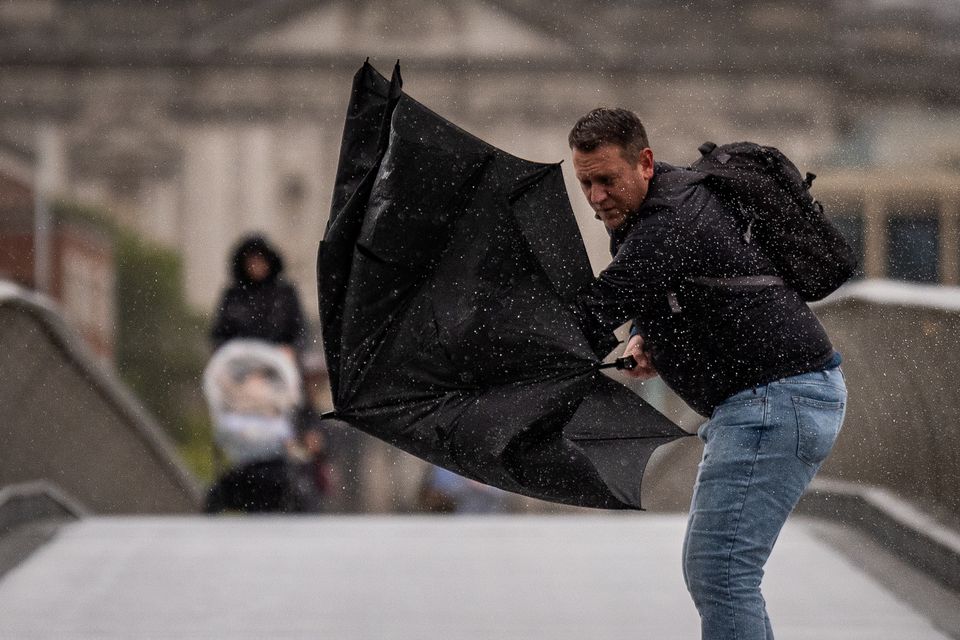 A man struggling with his umbrella on Millennium Bridge in London (Aaron Chown/PA)