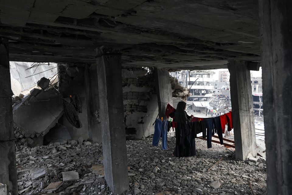 A Palestinian woman hangs the laundry inside her home, which was destroyed in the Israeli bombardment of the Gaza Strip (Jehad Alshrafi/AP)