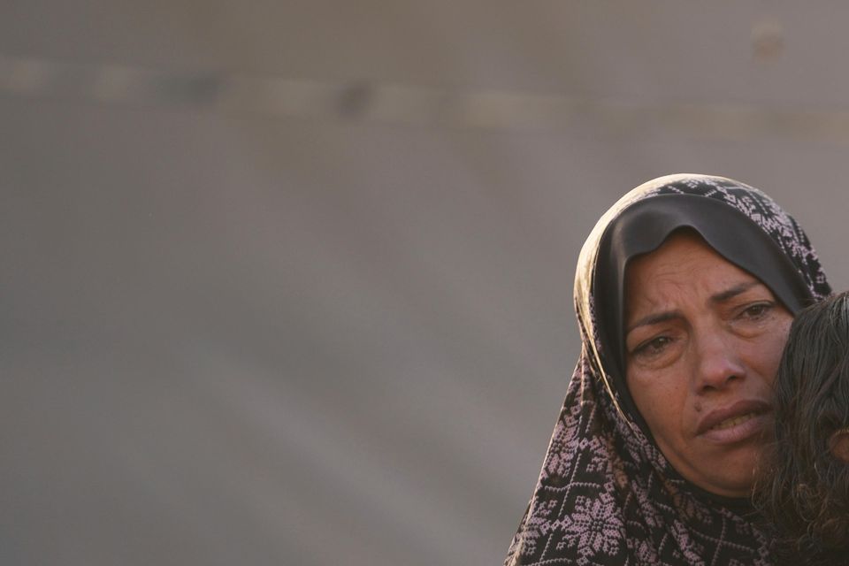 A Palestinian woman comforts a child after an Israeli strike hit a tent area in the courtyard of Al Aqsa Martyrs hospital in Deir al Balah on Monday (AP Photo/Abdel Kareem Hana)