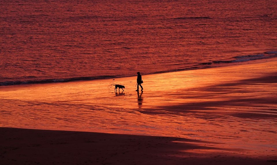 A person walks along Tynemouth Beach as the sun rises in North Shields (Owen Humphreys/PA)
