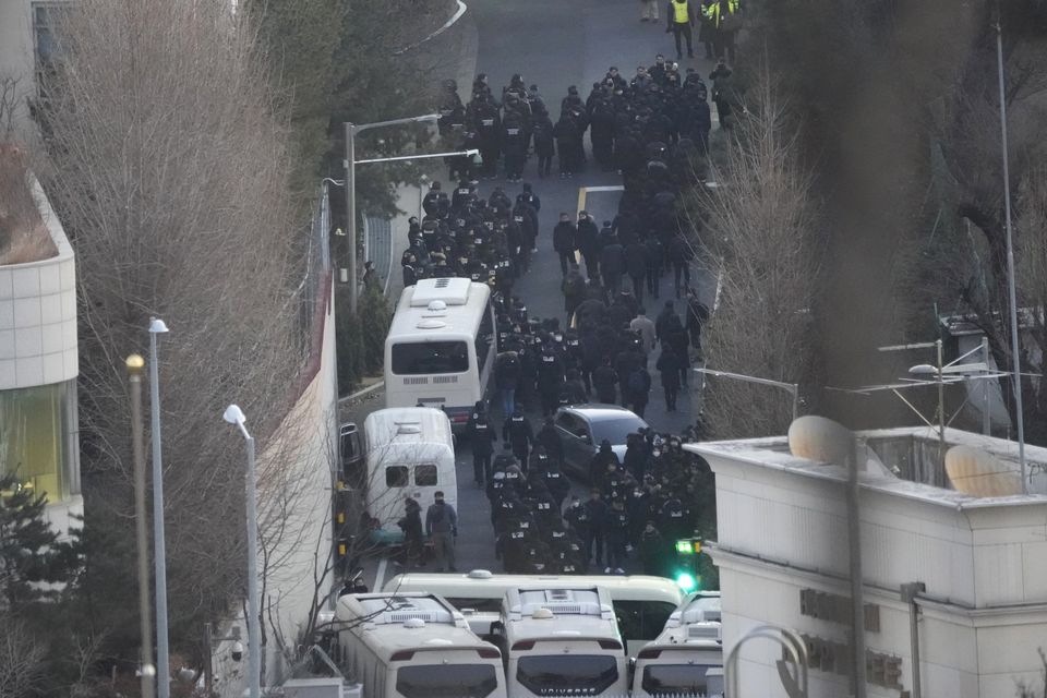 Investigators from the state anti-corruption agency and police officers make their way to the residence of impeached president Yoon Suk Yeol (Ahn Young-joon/AP)