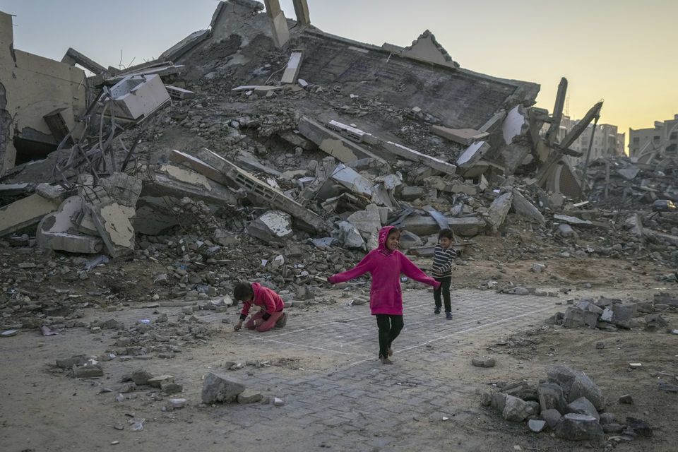 Palestinian children play next to a building destroyed by Israeli army strikes in the central Gaza Strip town of Khan Younis (AP/Abdel Kareem Hana)