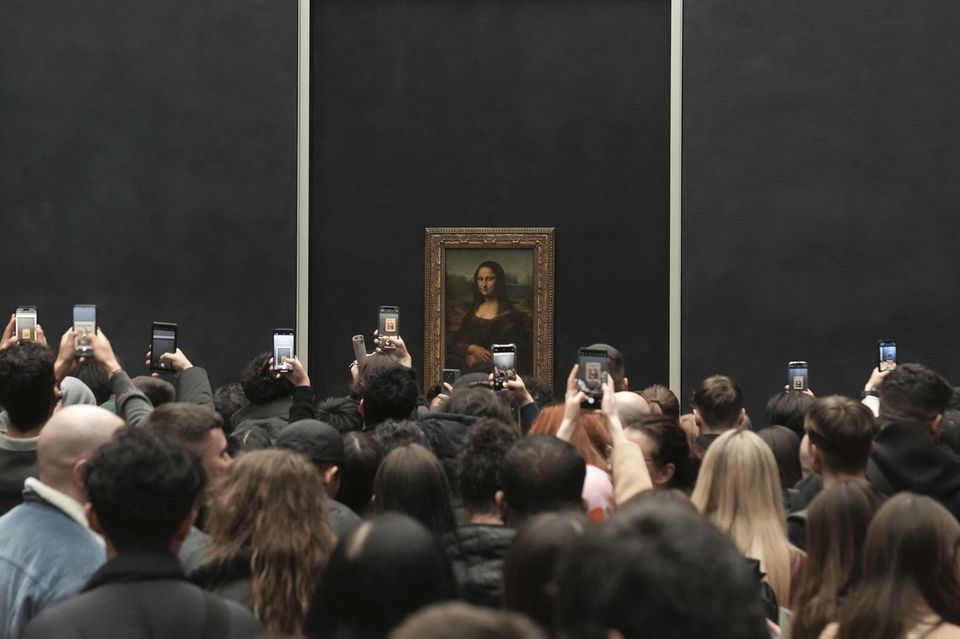 The Mona Lisa is displayed behind protective glass in a room that is often overcrowded by large, noisy queues of visitors (Thibault Camus/AP)