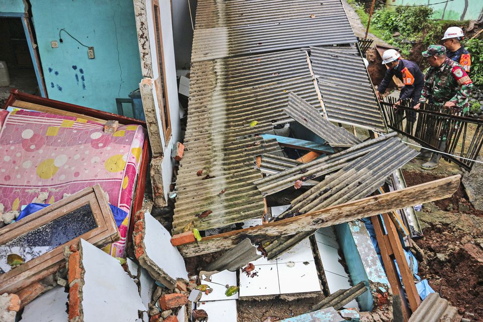 Rescuers clear up rubble from damaged houses at a neighbourhood affected by a landslide in Sukabumi, West Java, Indonesia (Rangga Firmansyah/AP)