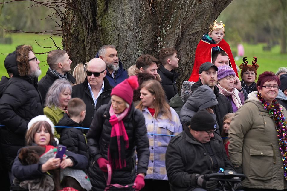 A young boy in a crown watches over the heads of the crowd gathered for the Christmas Day morning church service at Sandringham (Aaron Chown/PA)