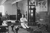 thumbnail: Shipyard worker William Parr (background) pictured in the Titanic gym along with instructor T W McCawley