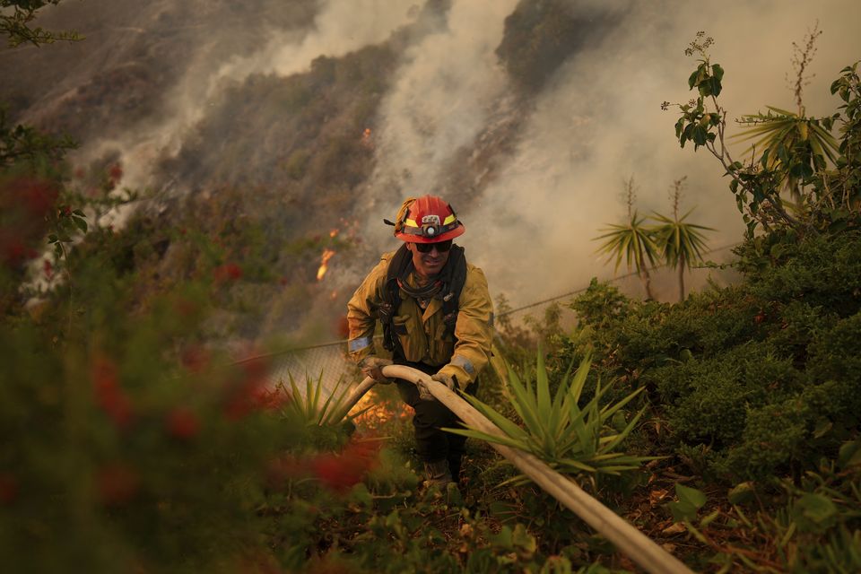 A firefighter sets up a hose while fighting the Palisades Fire (Eric Thayer/AP)