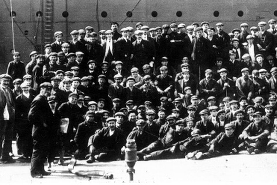A few of the 15,000 workmen employed by Harland and Wolff Ltd. at Queen's Island, Belfast, with Titanic in the background.