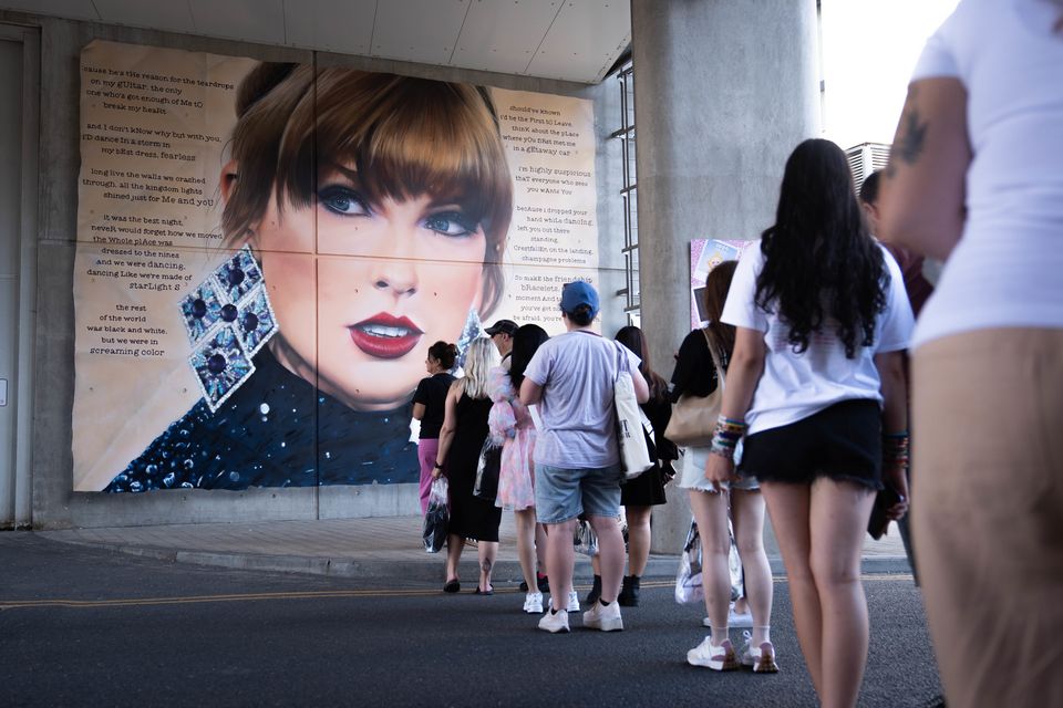 Swifties line up to pose in front of a mural outside Wembley. (James Manning/PA)