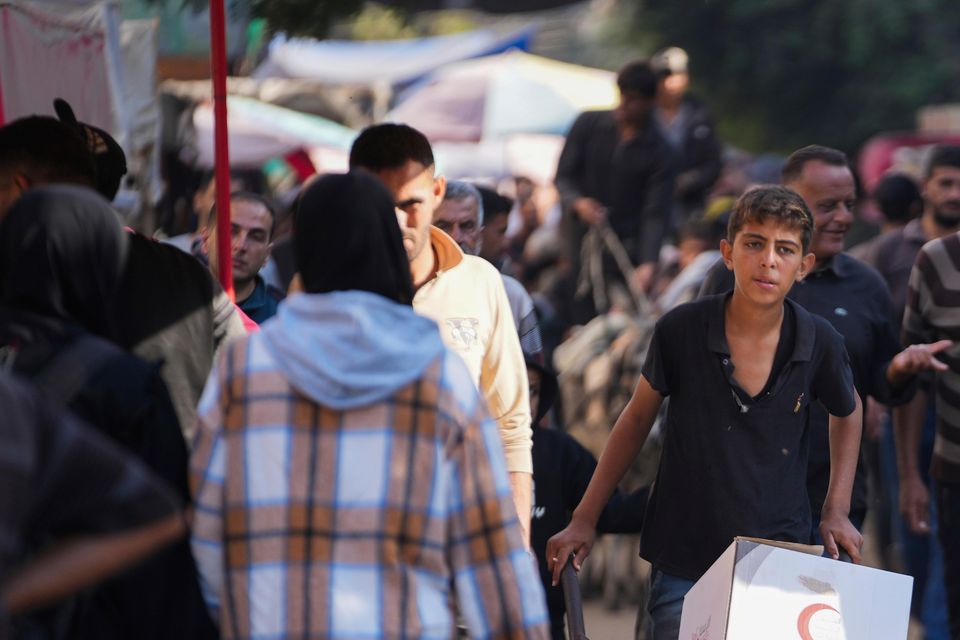 A Palestinian child carries humanitarian aid in Deir al-Balah (Abdel Kareem Hana/AP)