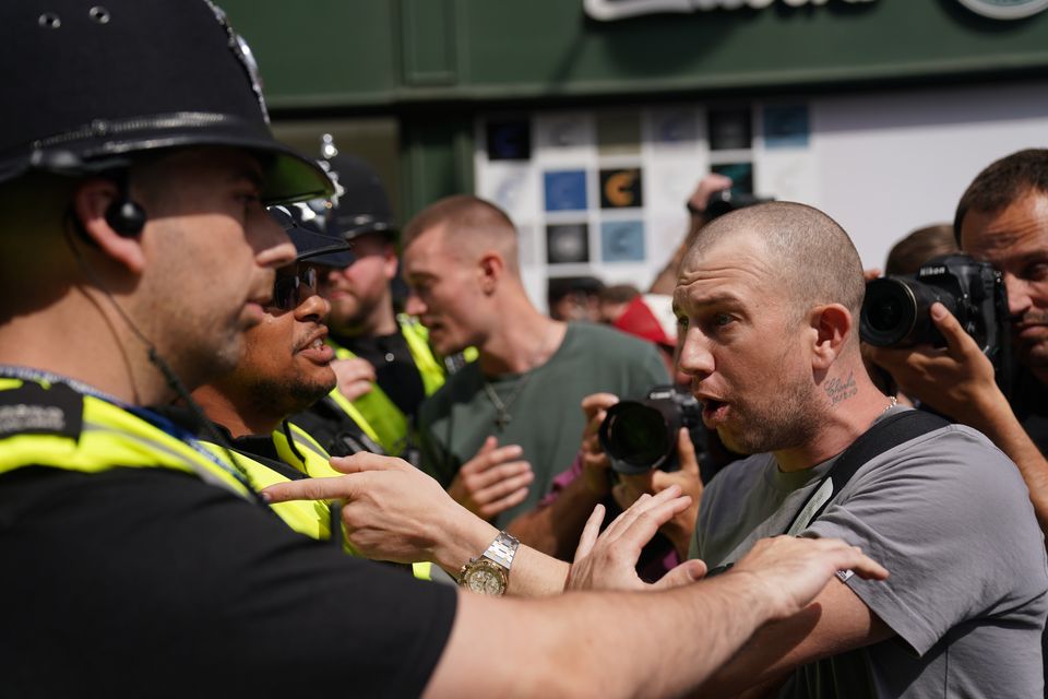 Police officers speak to a man as people protest in Nottingham’s Market Square (Jacob King/PA)