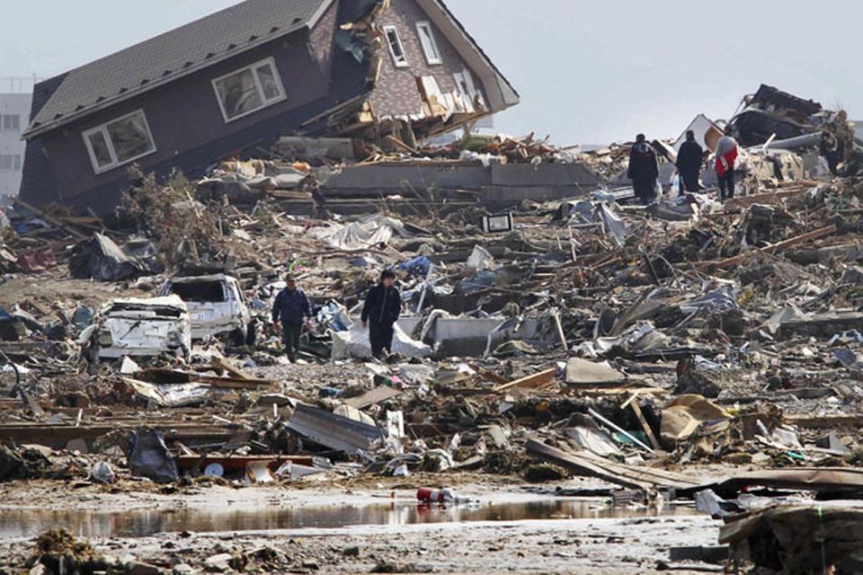 People walk in the rubble in Minamisanriku town, Miyagi Prefecture, northern Japan, Sunday, March 13, 2011, two days after a powerful earthquake-triggered tsunami hit the country's east coast. (AP Photo/The Yumiuri Shimbun) JAPAN OUT, CREDIT MANDATORY