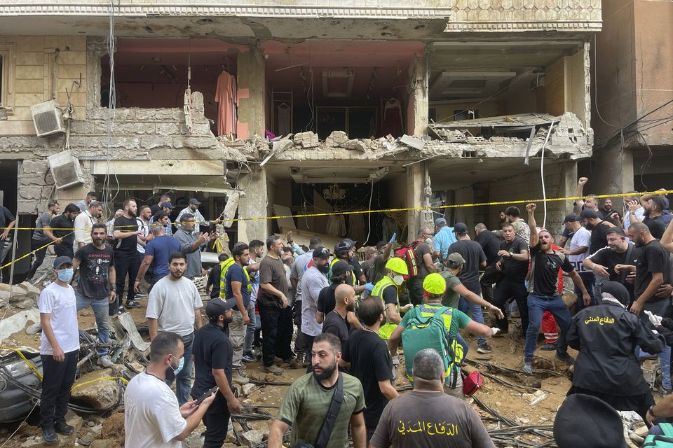 People gather near a damaged building at the scene of an Israeli missile strike in the southern suburbs of Beirut (Bilal Hussein/AP)