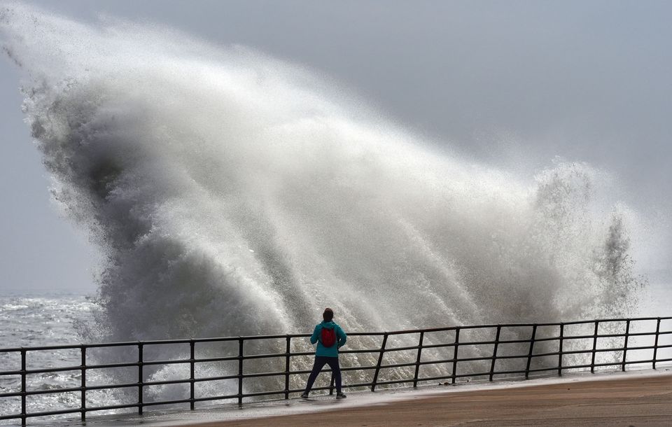 A spectator gets a close look at a huge wave in Whitley Bay (Owen Humphreys/PA)