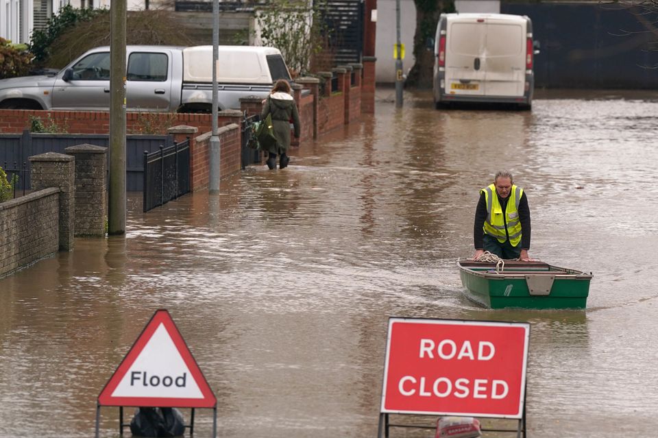 A flood warden pushes a boat in floodwater in Herefordshire after Storm Darragh (Jacob King/PA)