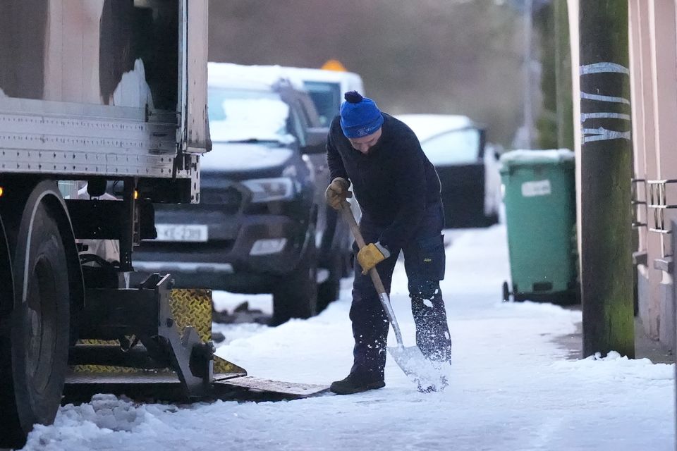 A man clears snow from the pathway in the village of Ballylynan in Co Laois (Niall Carson/PA)