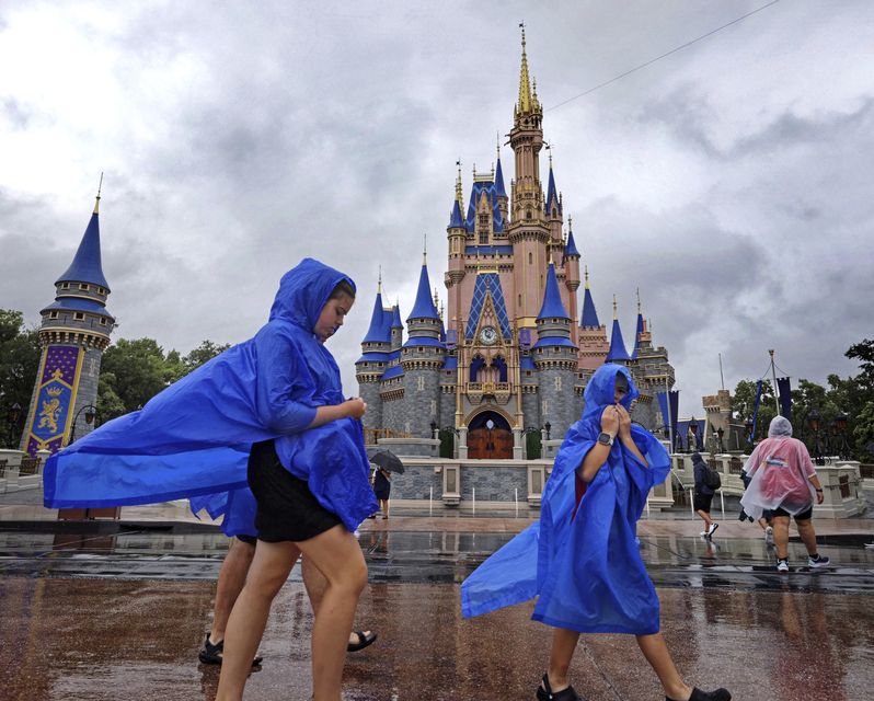 Vistiors at the Magic Kingdom at Walt Disney World brave the wind and rain (Joe Burbank/Orlando Sentinel/AP)