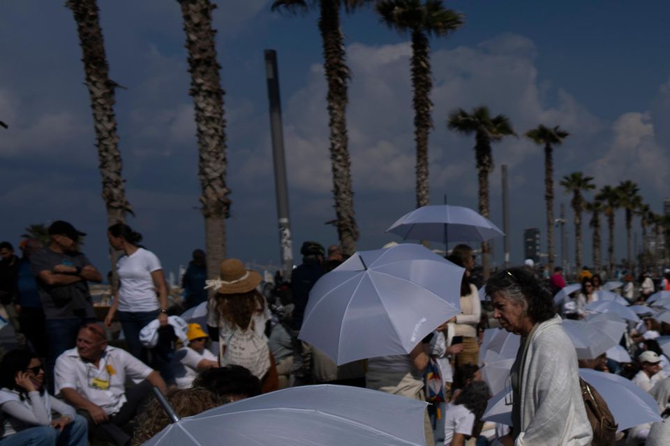 Activists sit on a road with white umbrellas during a protest calling for the release of hostages held in the Gaza Strip (Oded Balilty/AP)