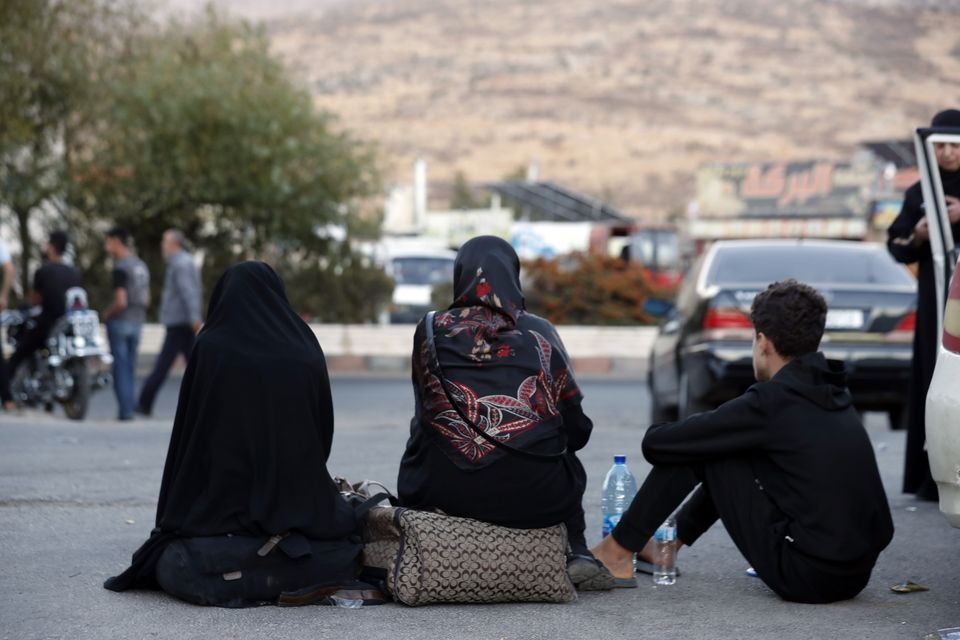 Lebanese people fleeing the Israeli bombardment, wait after crossing into Syria at the Syrian-Lebanese border crossing in Jdaidet Yabous (Omar Sanadiki/AP)