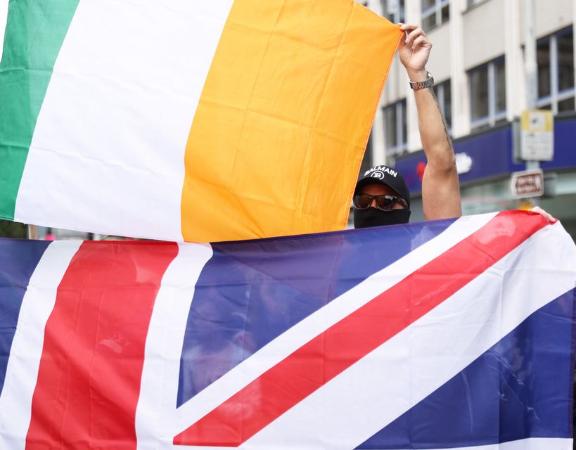 People taking part in an anti-immigration protest outside Belfast City Hall held the Irish flag and the Union flag (Peter Morrison/PA)