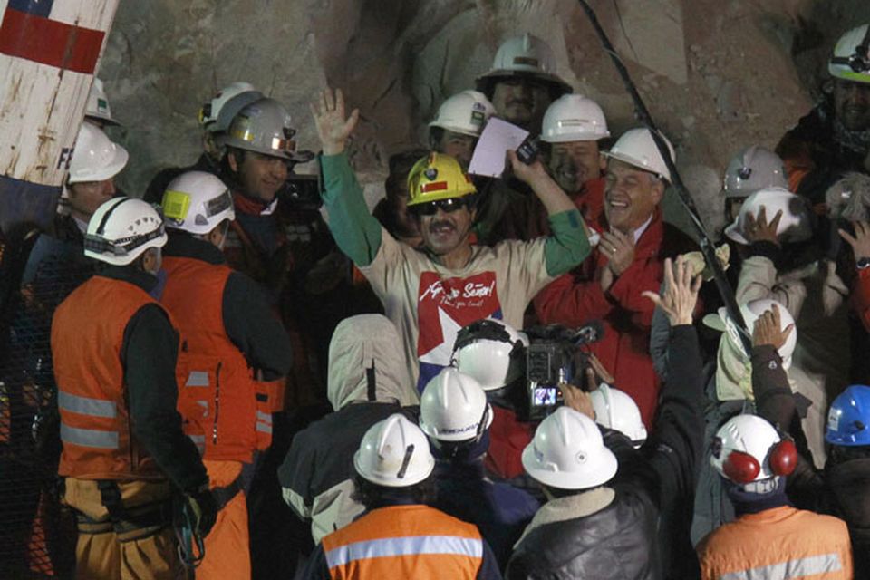 Rescued miner Juan Andres Illanes Palma, center,  third miner to be rescued, salutes at his arrival to the surface from the collapsed San Jose gold and copper mine where he was trapped with 32 other miners for over two months near Copiapo, Chile, Wednesday Oct. 13, 2010.at the San Jose Mine near Copiapo, Chile Wednesday, Oct. 13, 2010. Center right is Chile's President Sebastian Pinera.(AP Photo/Roberto Candia)