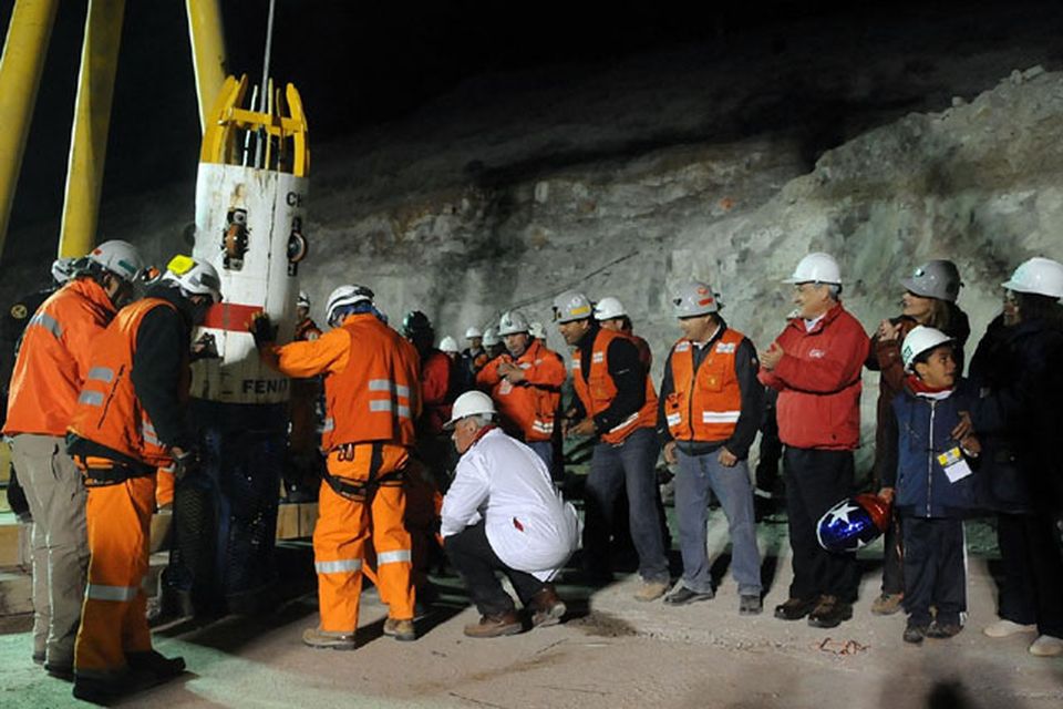 In this photo released by the Chilean presidential press office, Chile's President Sebastian Pinera, fourth right, applauds while the capsule with the first rescued miner Florencio Avalos comes out from the collapsed San Jose gold and copper mine where he was trapped with 32 other miners for over two months near Copiapo, Chile, early Wednesday, Oct. 13, 2010.  (AP Photo/Jose Manuel de la Maza, Chilean presidential press office)